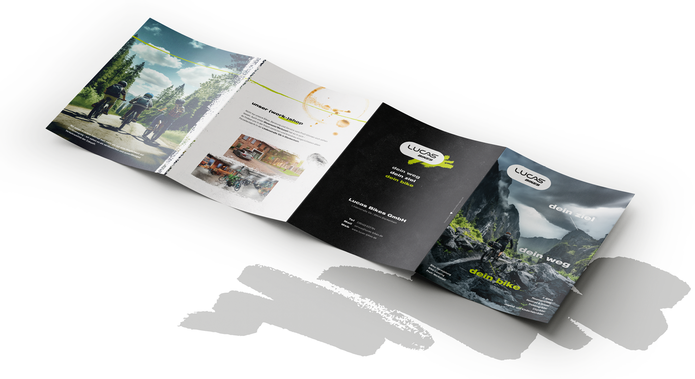 Eine offene, vierseitige Broschüre mit Bildern von Radfahrern, Berglandschaften und Text, der für Outdoor-Radfahren und E-Bikes wirbt. Das Design verwendet grüne und schwarze Farben mit malerischen Naturfotos, modernen Grafiken und einer subtilen Anspielung auf den dynamischen Geist der Tanzschule Fischer.