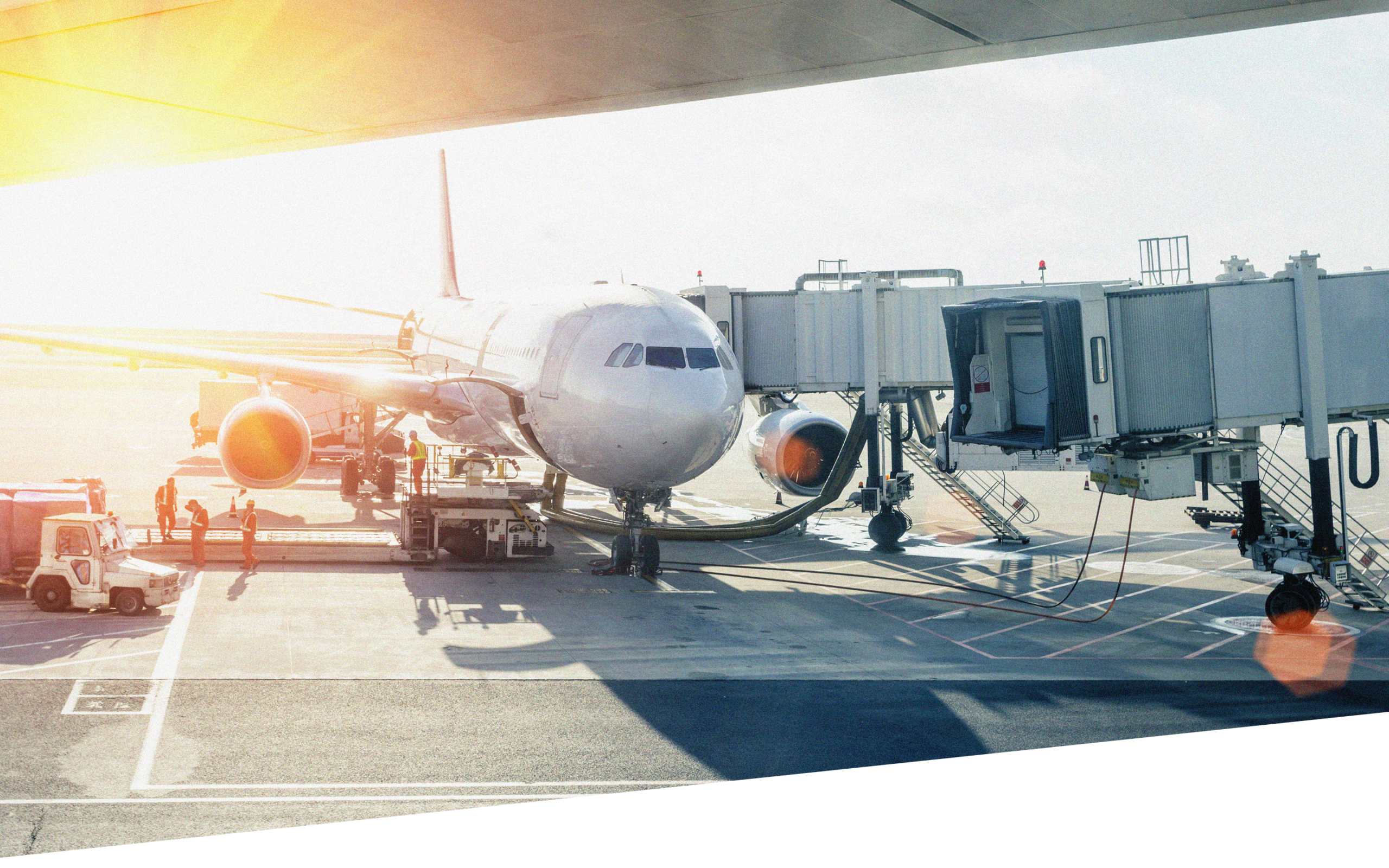 Ein Verkehrsflugzeug ist an einem Flugsteig geparkt und mit einer Fluggastbrücke verbunden, während Bodenpersonal und Fahrzeuge - darunter auch die von Geithe & Ußner Hygienefachhandel - bei hellem Sonnenlicht um das Flugzeug herum arbeiten.